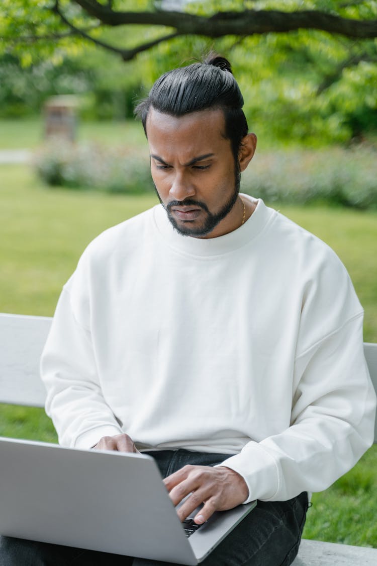 A Man In White Sweater Using A Laptop In The Park