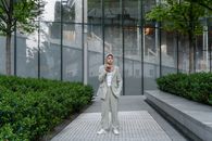 Woman in Gray Coat Standing on Gray Brick Floor
