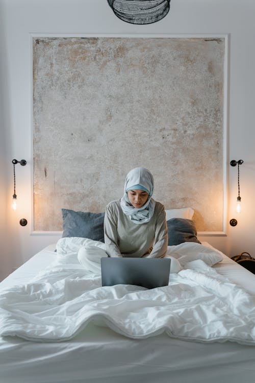 A Woman Using Laptop on the Bed