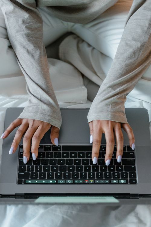 Free Close-up view of a woman's hands typing on a laptop keyboard while sitting comfortably indoors. Stock Photo