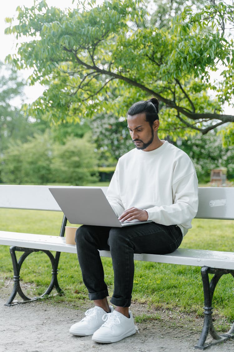 A Man Sitting On The Bench Using Laptop