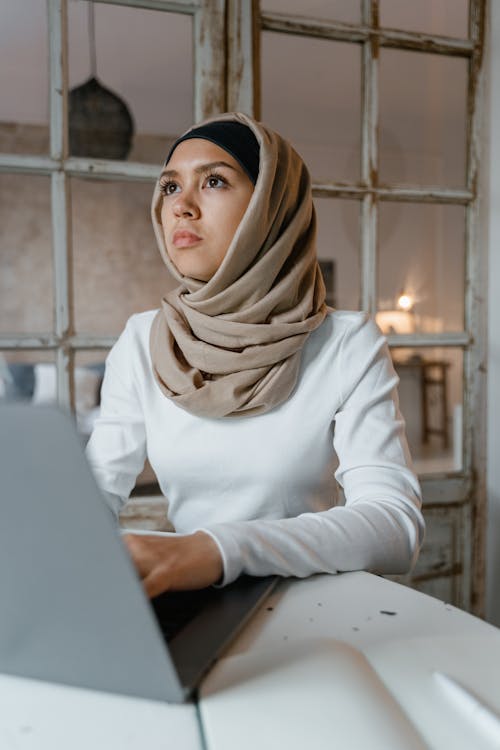 Woman in White Long Sleeve Shirt Wearing Brown Hijab Looking Afar