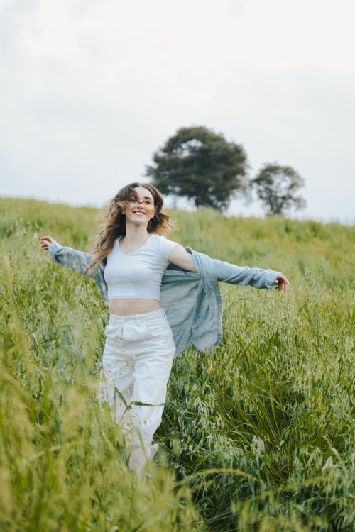 Free Carefree woman in white embracing nature in a green field. Perfect for lifestyle and fashion themes. Stock Photo