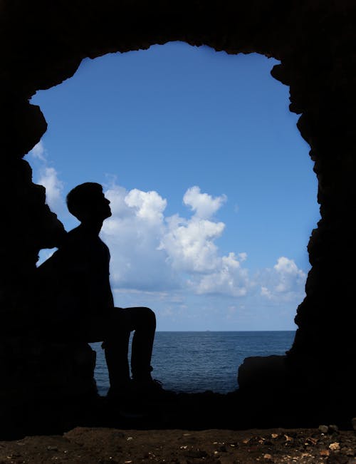 Silhouette of a Man in a Cave near the Sea