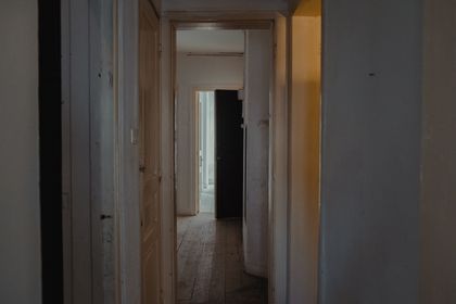 Dimly lit apartment hallway with wooden doors — photo by Faruk Tokluoglu on Pexels