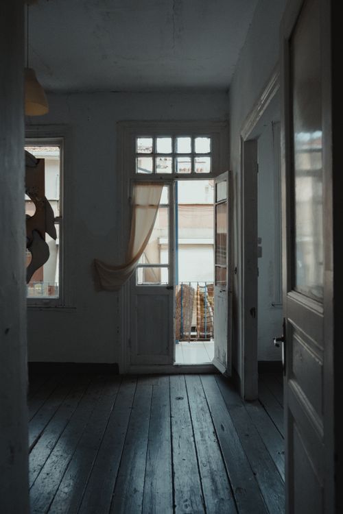 Free Interior shot of a dark room with wooden floors, open door, and natural light streaming in. Stock Photo