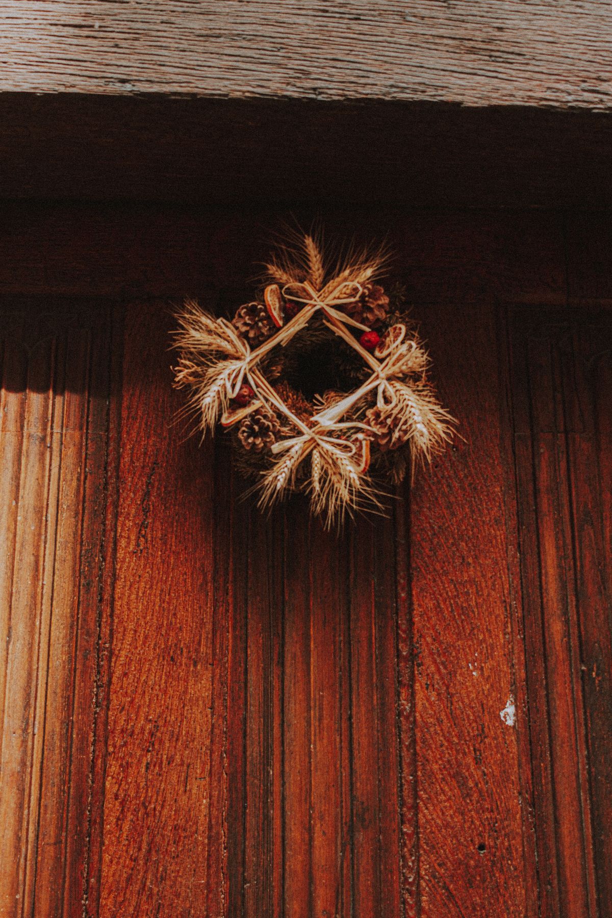 Close-up of a rustic wooden door with a natural decorative twig wreath
