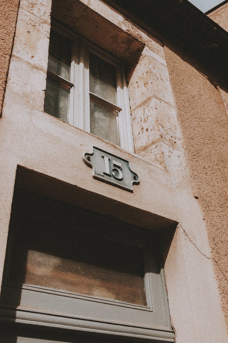 Metal Plate With Number On A Brown Concrete Wall