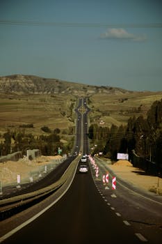 Empty highway stretching through hills under a clear sky, perfect for travel themes.