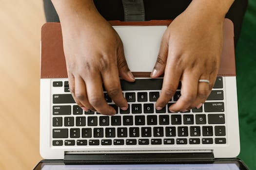 Close-up of hands typing on a laptop keyboard, showcasing productivity and technology.