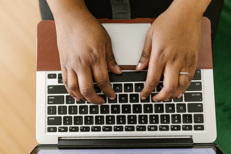 Overhead Shot Of A Person's Hands Typing On A Laptop Keyboard