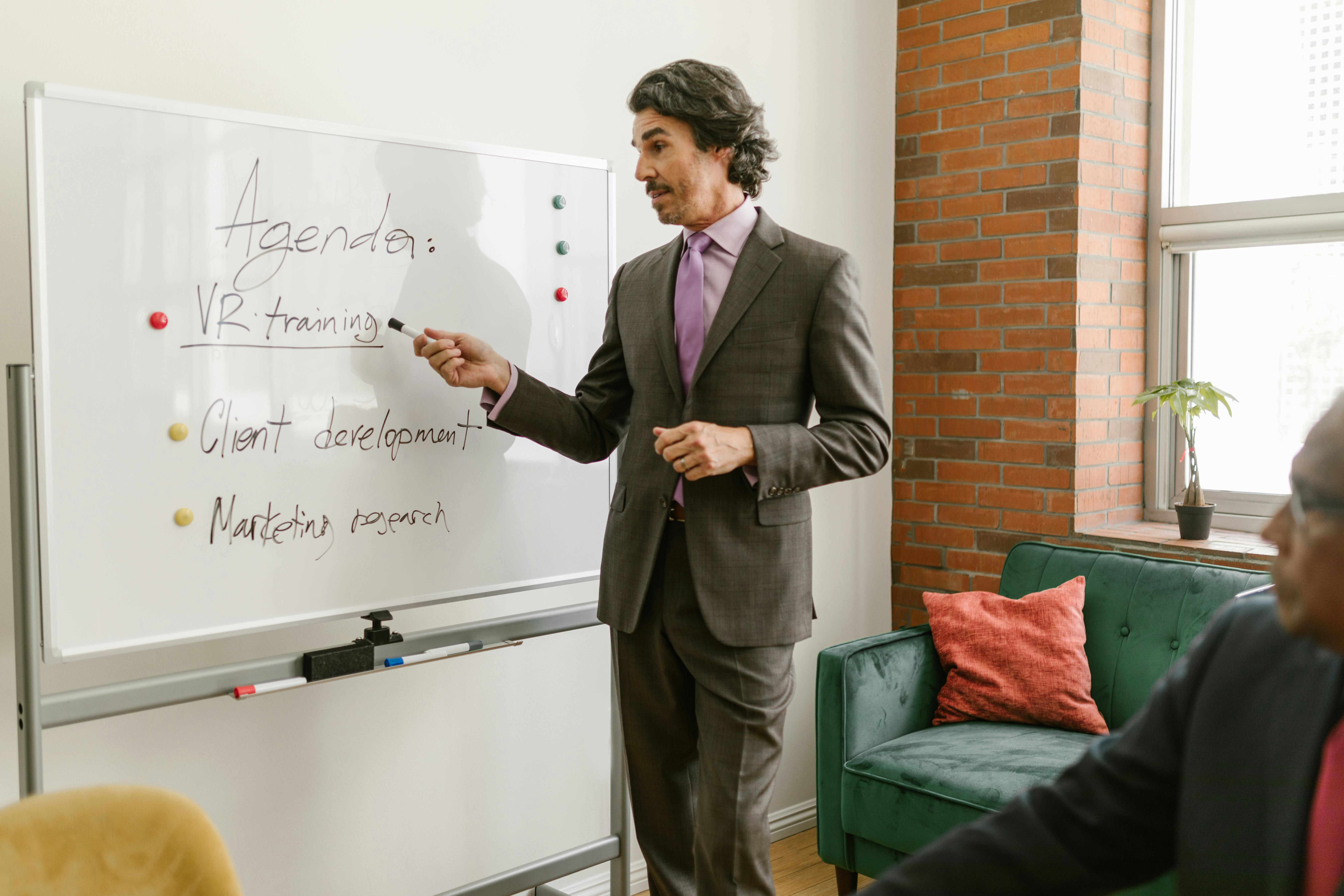 man in business attire discussing and standing in front of his colleagues