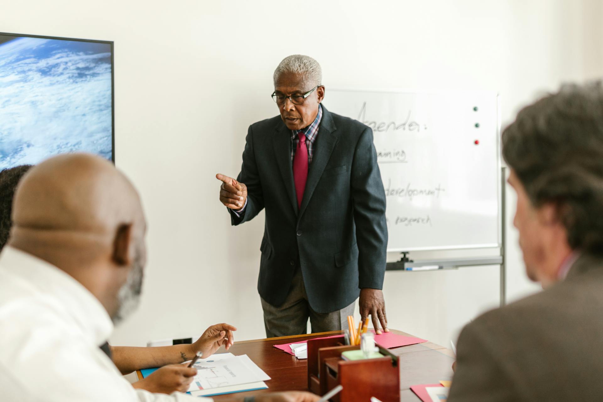 Senior man leading a business meeting with colleagues in a professional office setting.