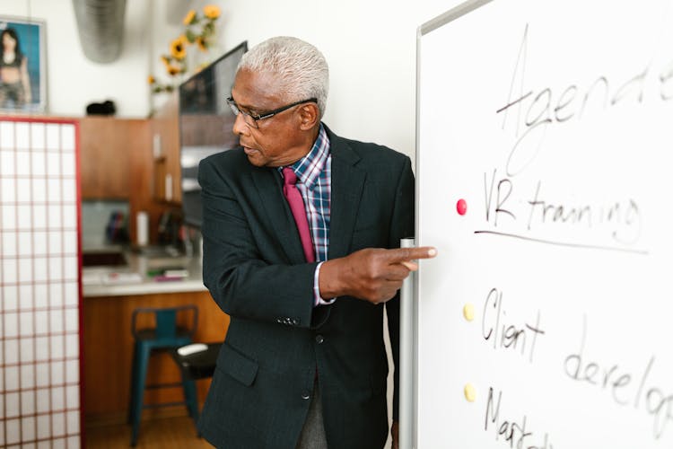 Man Pointing Finger At A White Board On HIs Presentation                While Discussing