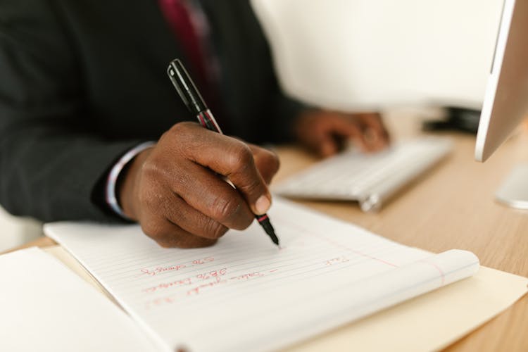 Man Hand Holding Pen And Writing In Notepad