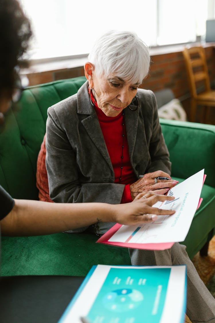 An Elderly Woman Looking The Report Papers