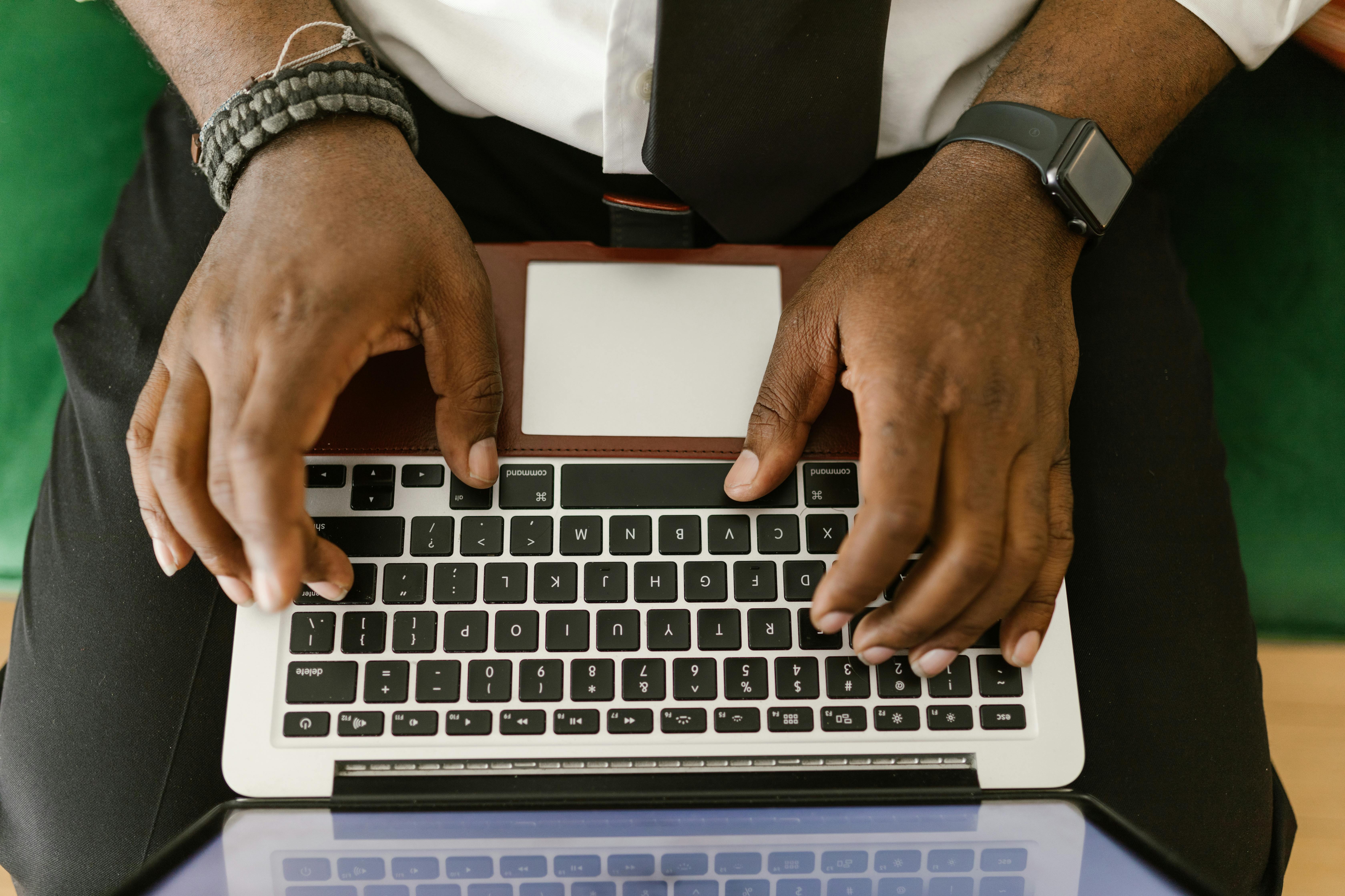 Close-up of a man's hands typing on a laptop, showcasing technology and connectivity.
