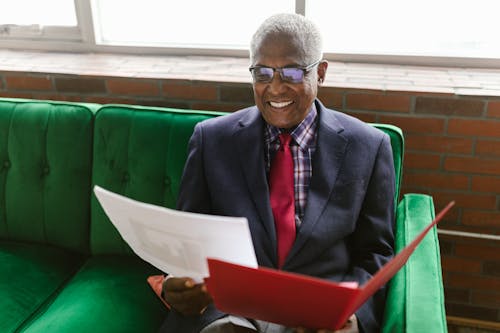 An Elderly Man in Blue Suit Smiling while Sitting on the Couch