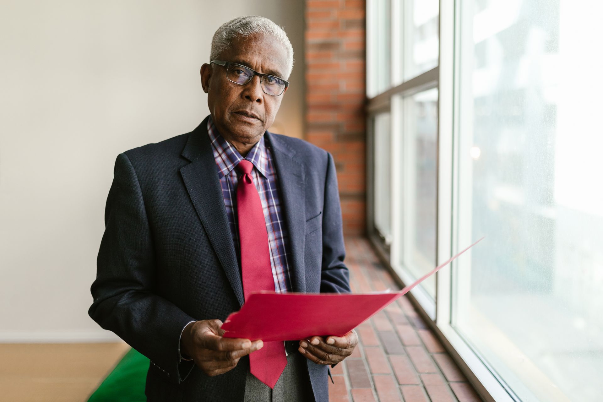 Gray Haired Man Holding a Red Folder