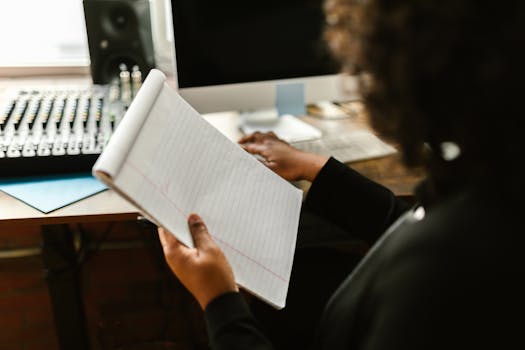 A close-up image of a person holding a notepad in a modern office with audio equipment.