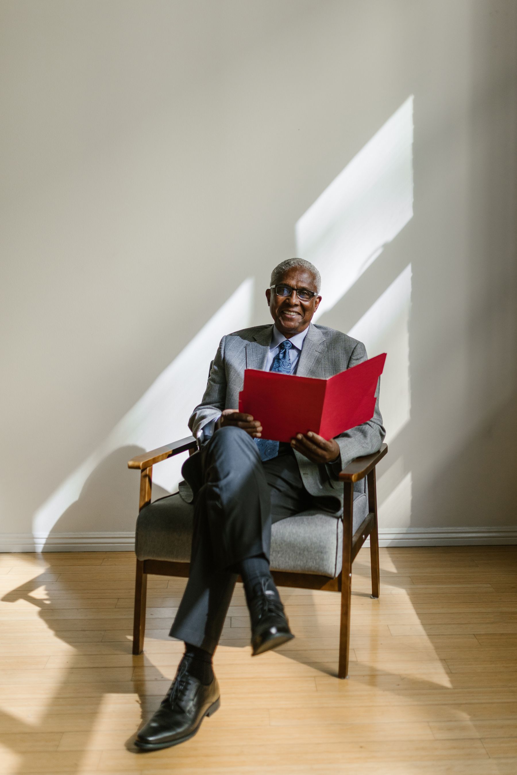 A business owner seated in a sunlit room with a red folder