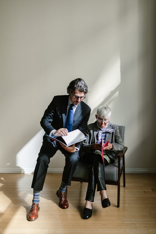 Woman and Man in Suits Sitting and Reading