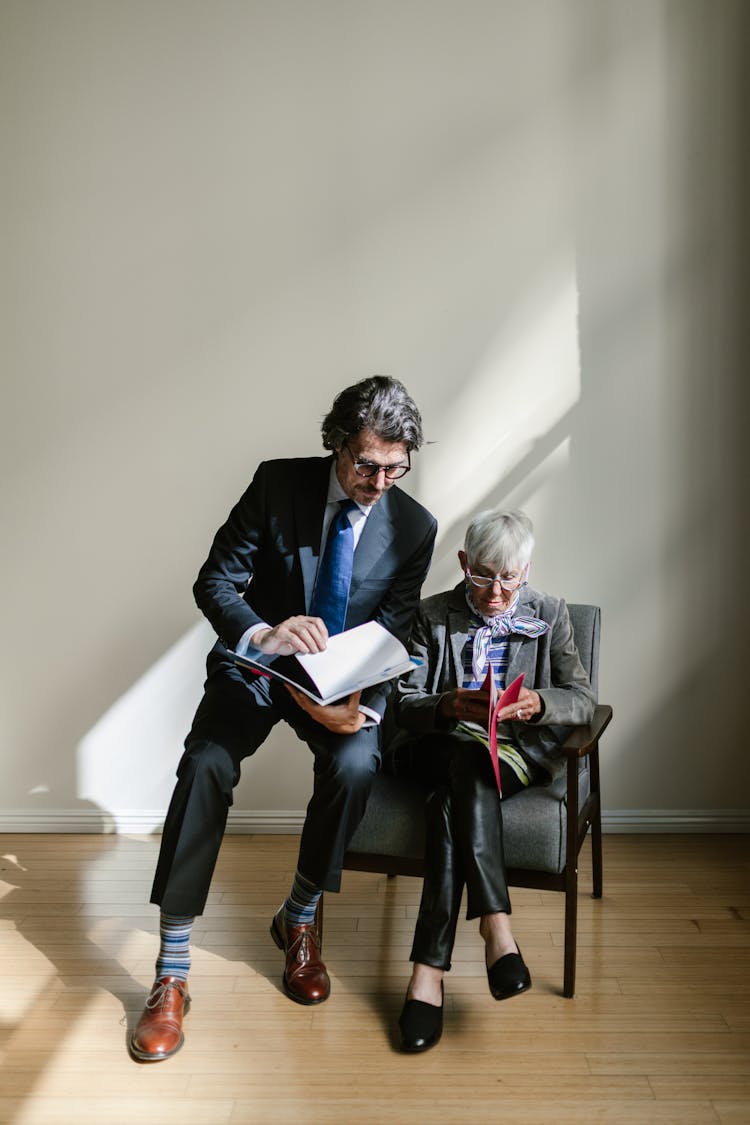 Woman And Man In Suits Sitting And Reading