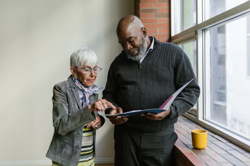 An Elderly Man and Woman Having Conversation while Looking at the Folder