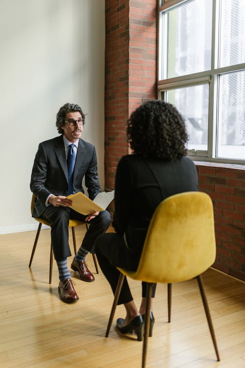 An image of a Dallas woman and man looking at each other while sitting on chairs