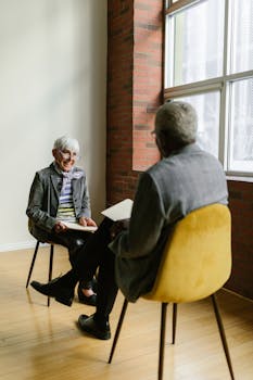 Two senior adults engage in a friendly discussion in a modern office setting.