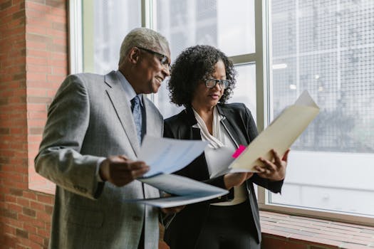 Two business professionals discussing documents with a city view in the background.