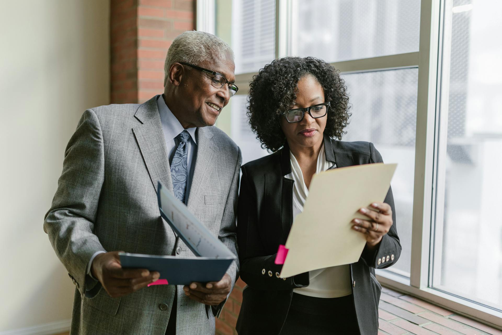 An Elderly Man and a Woman Looking at the Folder while Having a Conversation