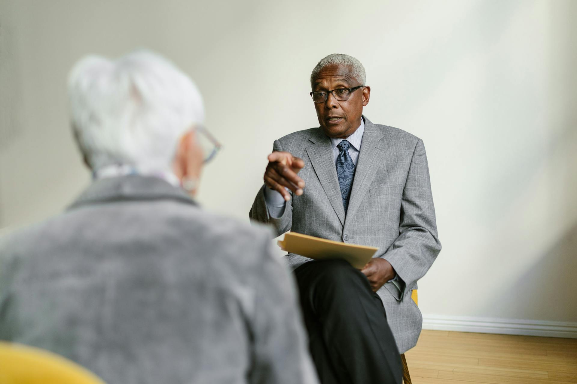 Two senior adults in a business meeting indoors, discussing important matters.