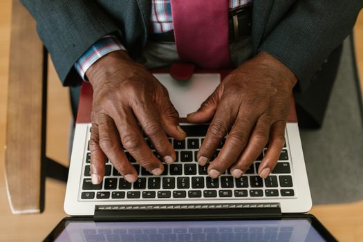 Close-up of adult hands typing on a laptop keyboard, capturing the detail and focus of work.