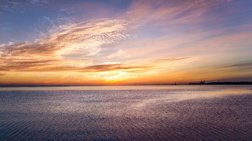 Free A stunning sunset over a calm ocean with vibrant clouds and tranquil waters. Stock Photo