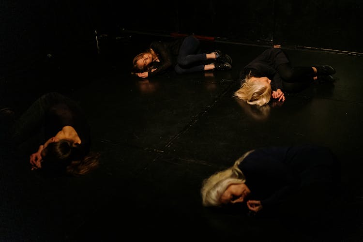 Women Lying In Fetal Position On Stage Floor