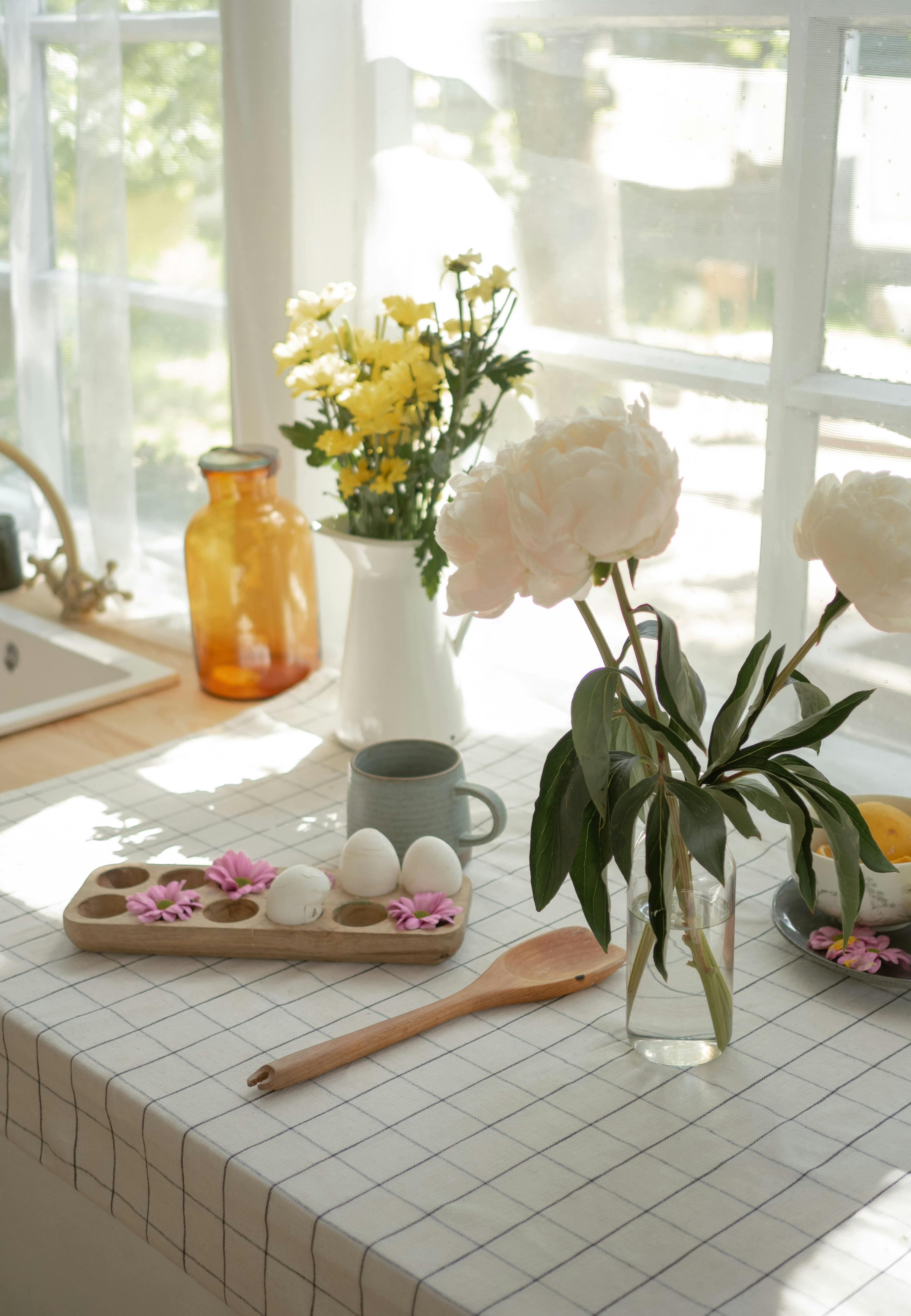 A sunny kitchen setting featuring flowers, eggs, and decor on a table.
