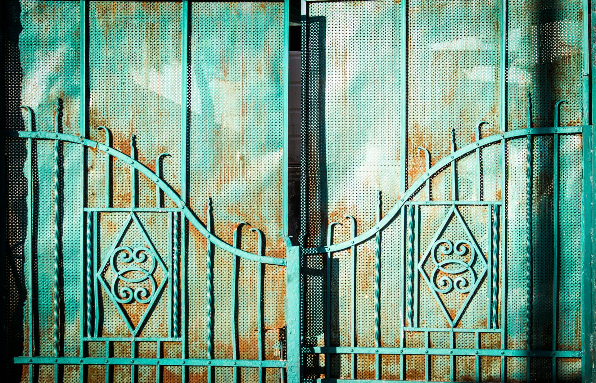 A rustic turquoise metal gate with intricate decorative patterns, perfect for outdoor design themes.