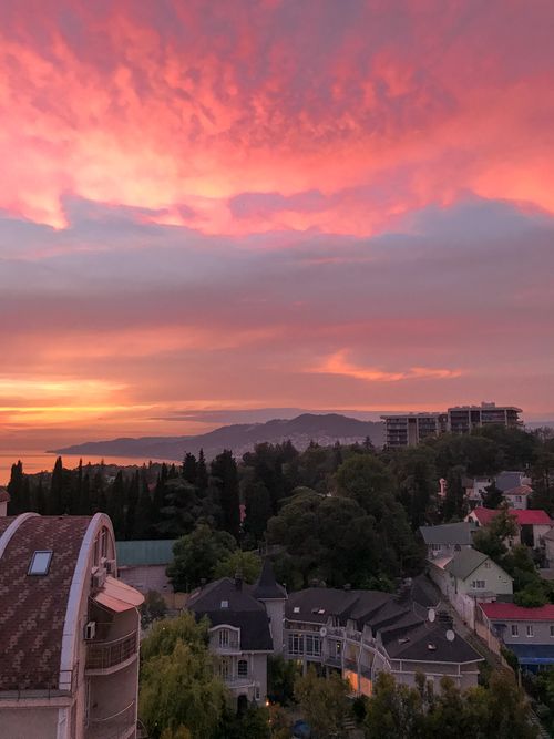 Free A stunning sunset casts vibrant colors over a cityscape with distant mountains. Stock Photo