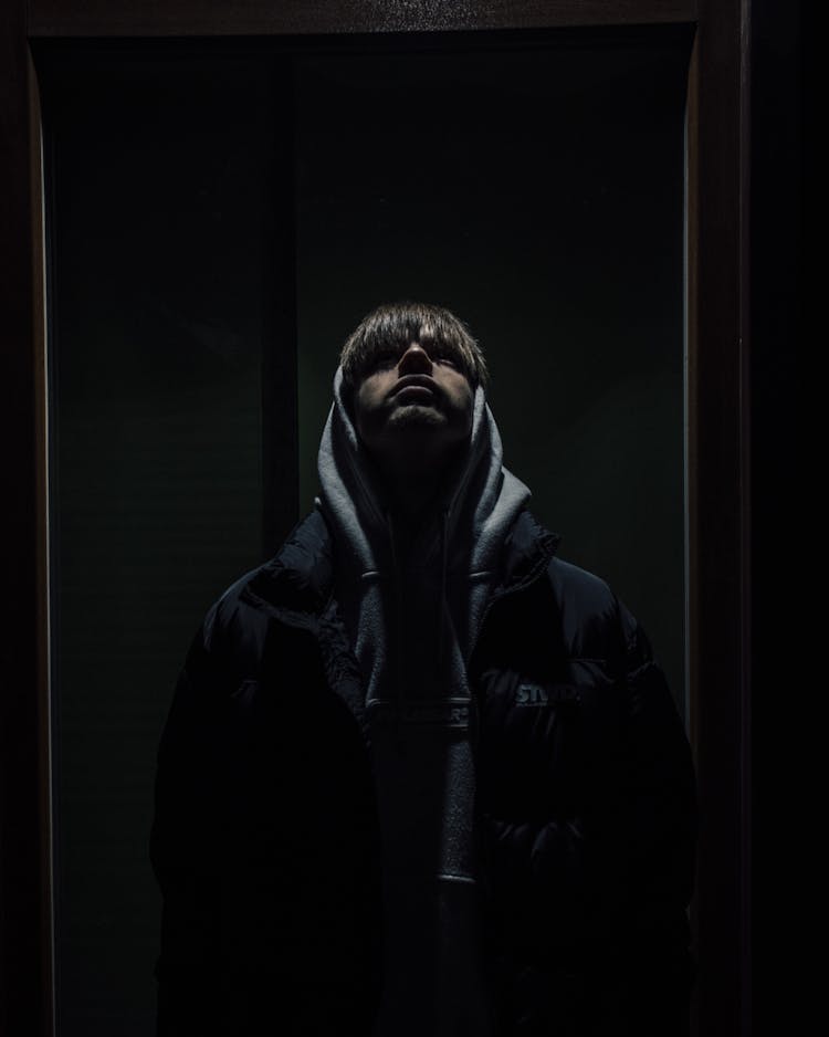 Man In Gray Hood And Black Coat Looking Up