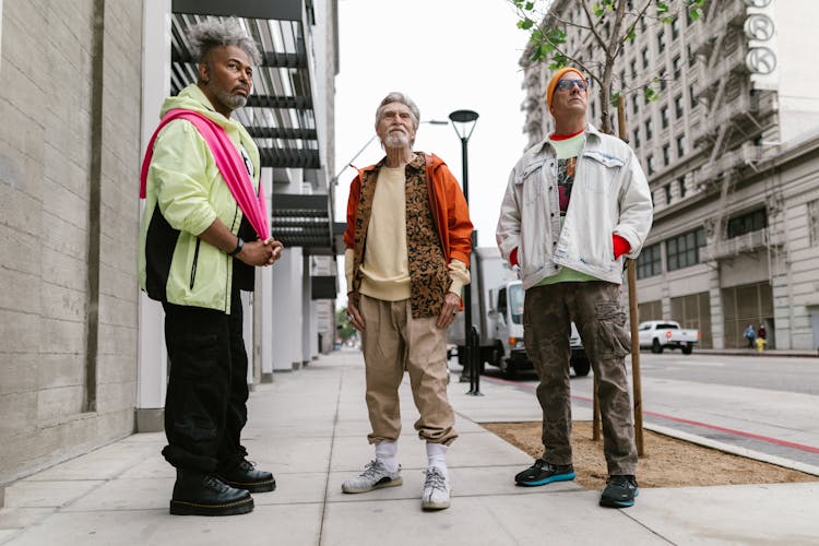 A Group Of Elderly Men Standing On The Street While Wearing Stylish Clothes