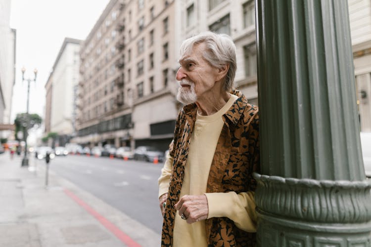 Elderly Man Leaning On The Pole 