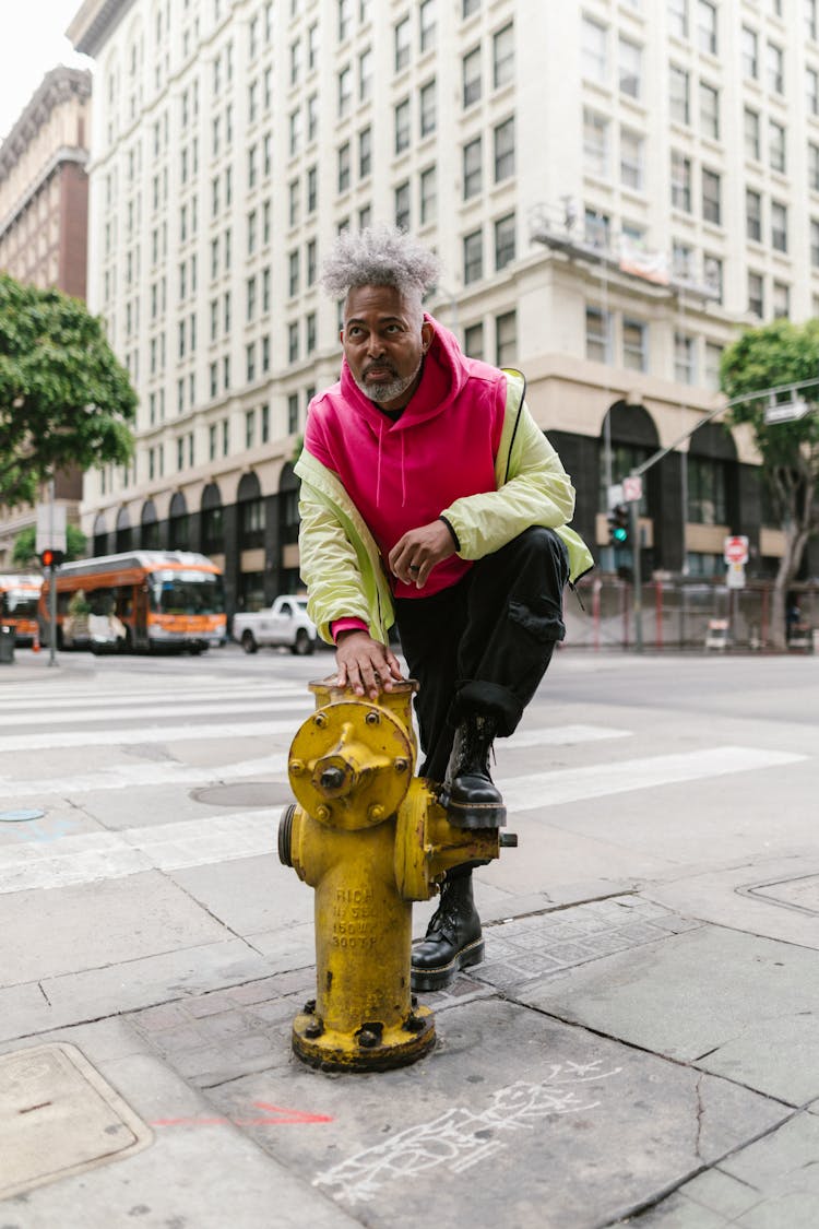 Gray Haired Man Stepping On A Yellow Fire Hydrant