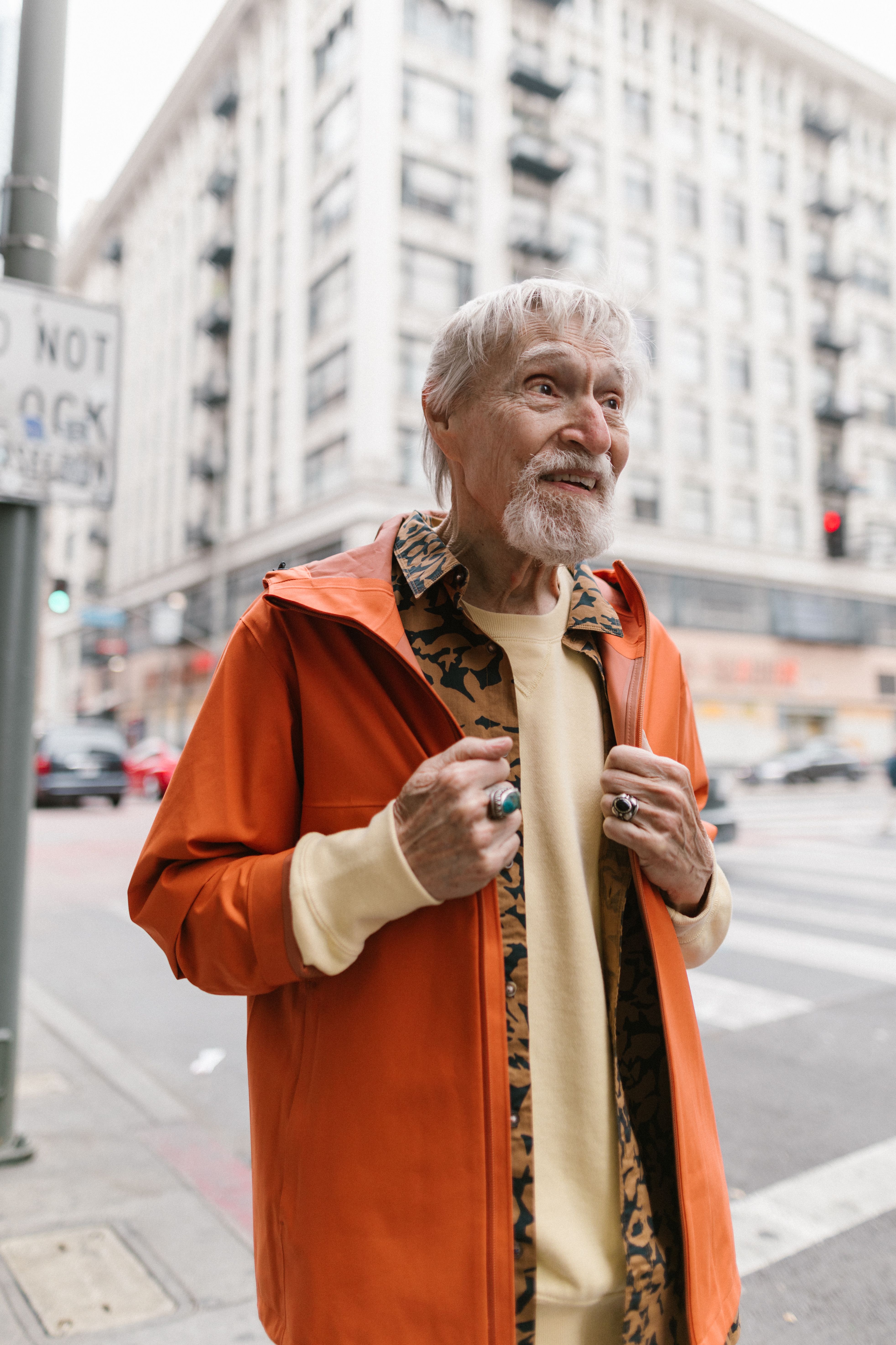 Senior man showcasing hip street style in a vibrant orange jacket.