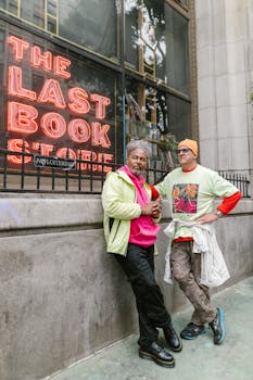 Two stylish men posing outside 'The Last Book Store', showcasing vibrant urban fashion.