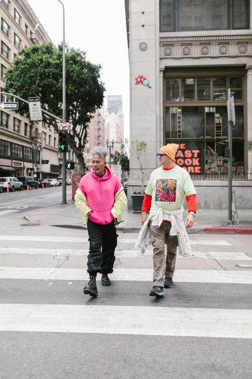 Free Two stylish men walk across a city street, showcasing trendy fashion in an urban setting. Stock Photo
