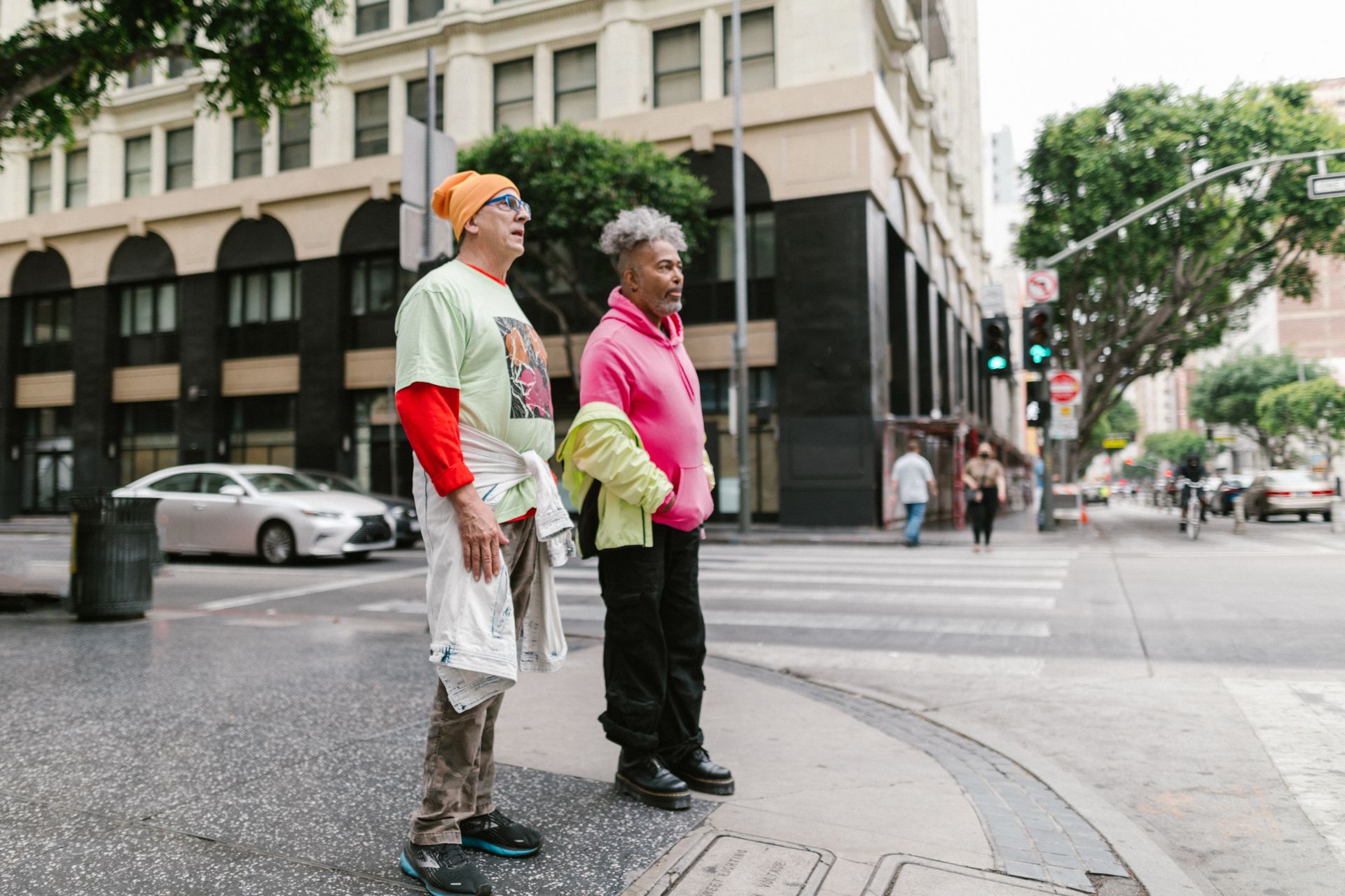 Elderly men in vibrant street fashion standing at a city intersection.