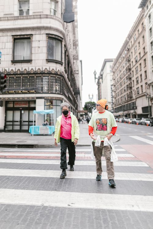 Free Two stylish men walk across a city street in fashionable attire, showcasing urban street style. Stock Photo