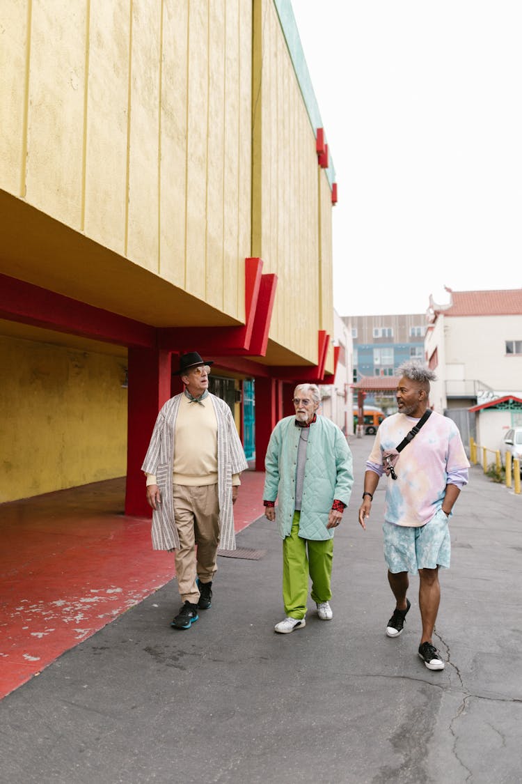 A Group Of Elderly Men Walking On The Street While Having Conversation