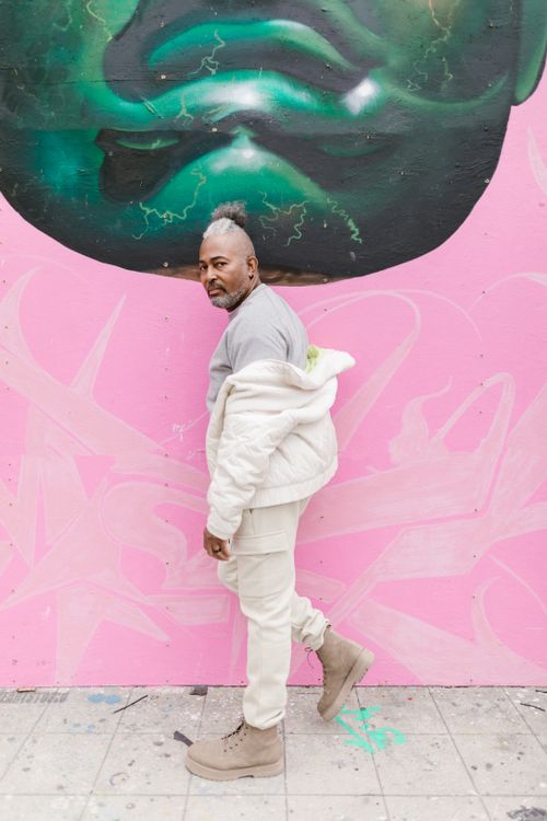 Free Portrait of a man in fashionable outfit standing against colorful graffiti wall on city street. Stock Photo